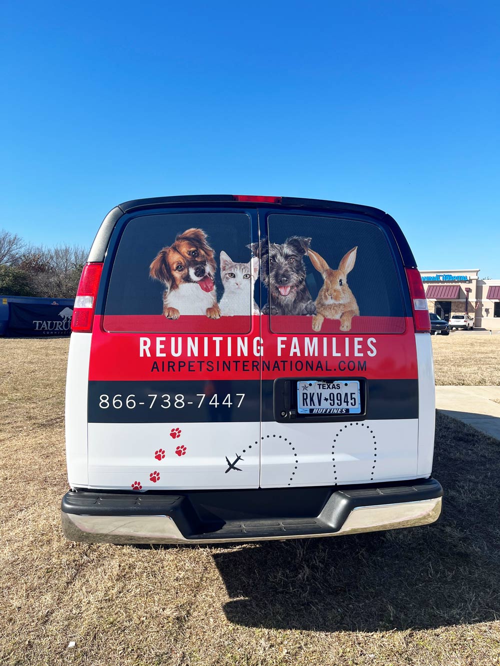 white van used for ground pet transport with animal stickers at the back.